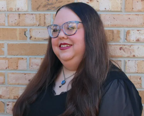 A woman standing in front of a brick wall.