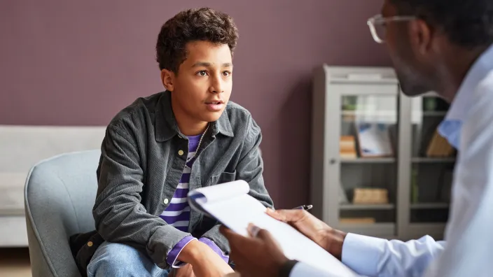 Teenage boy talking to doctor in office