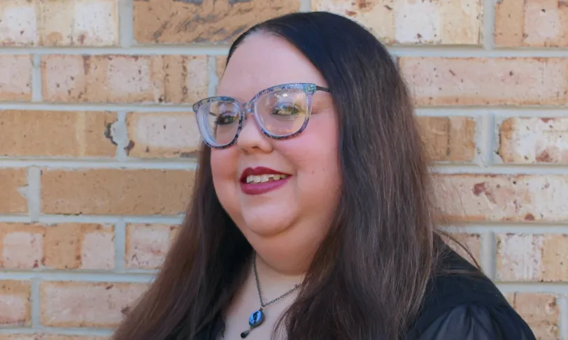 A woman standing in front of a brick wall.