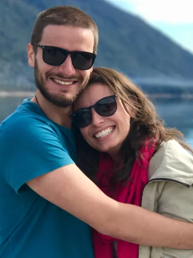 A couple hug while near a lake.