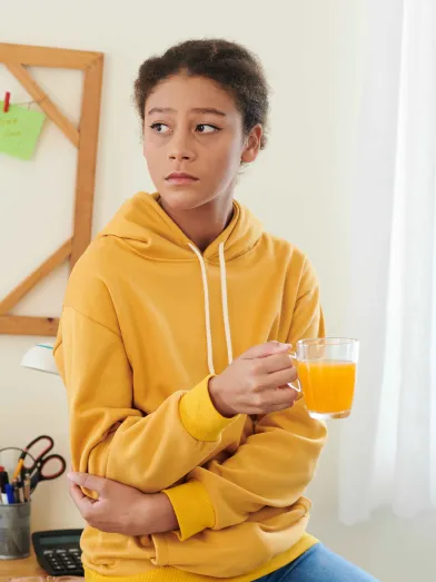 Sad teenage girl holding glass of orange juice